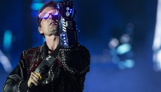 O líder do Muse, Matt Bellamy, com óculos e luva, todo paramentado com o figurino inicial do show