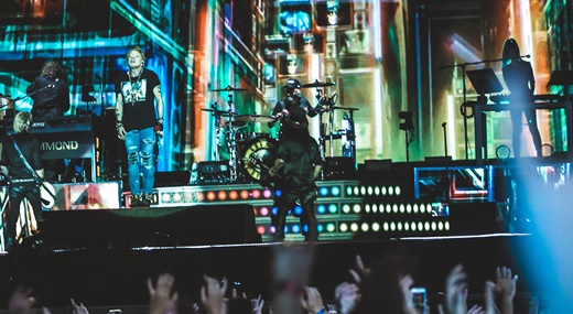 Paisagem do palco do show do Guns N'Roses, com a imagem do telão se confundindo com os músicos